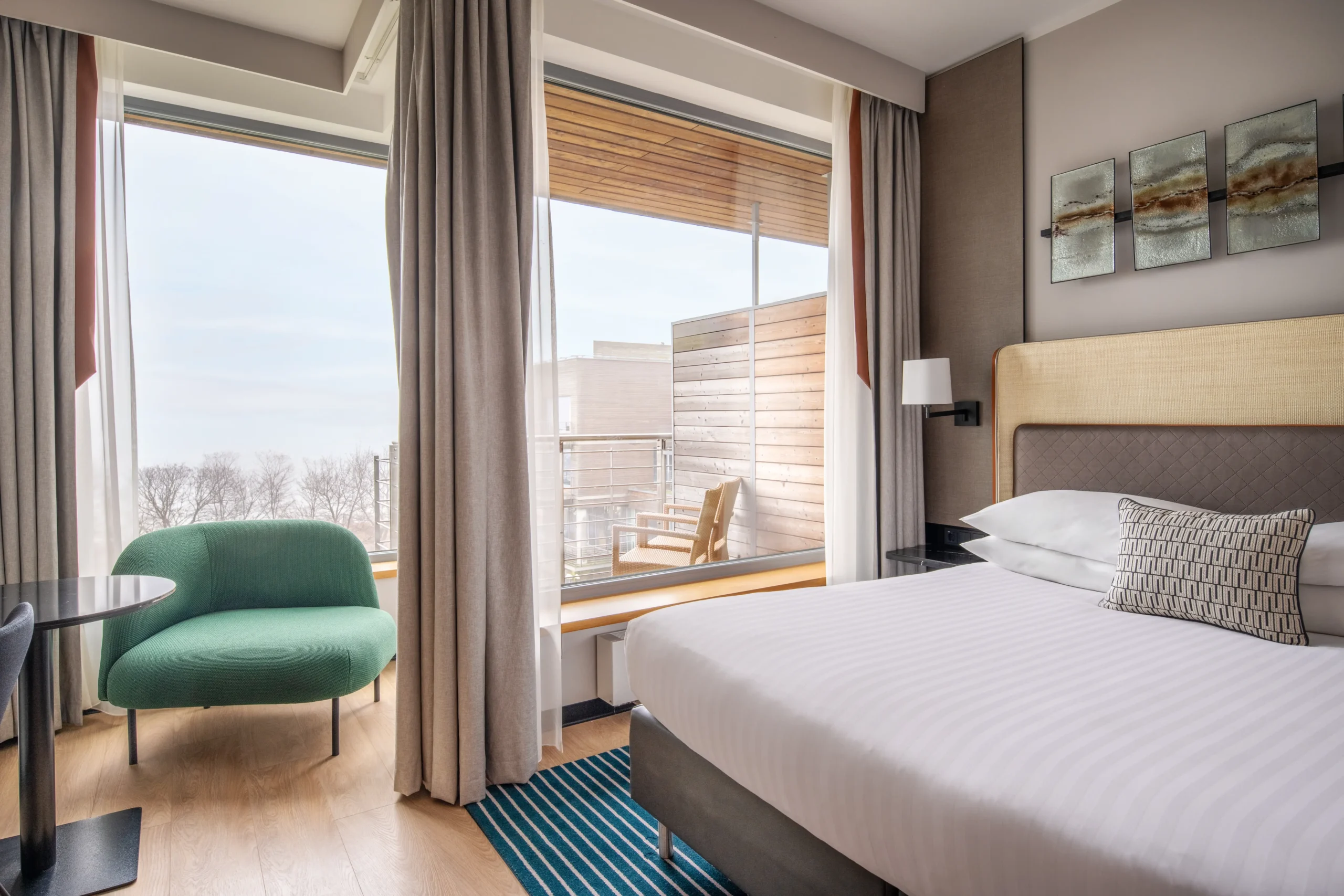 Nowoczesny pokój hotelowy z łóżkiem, stolikiem nocnym, fotelem i przeszklonym balkonem – wykończenie hoteli i restauracji