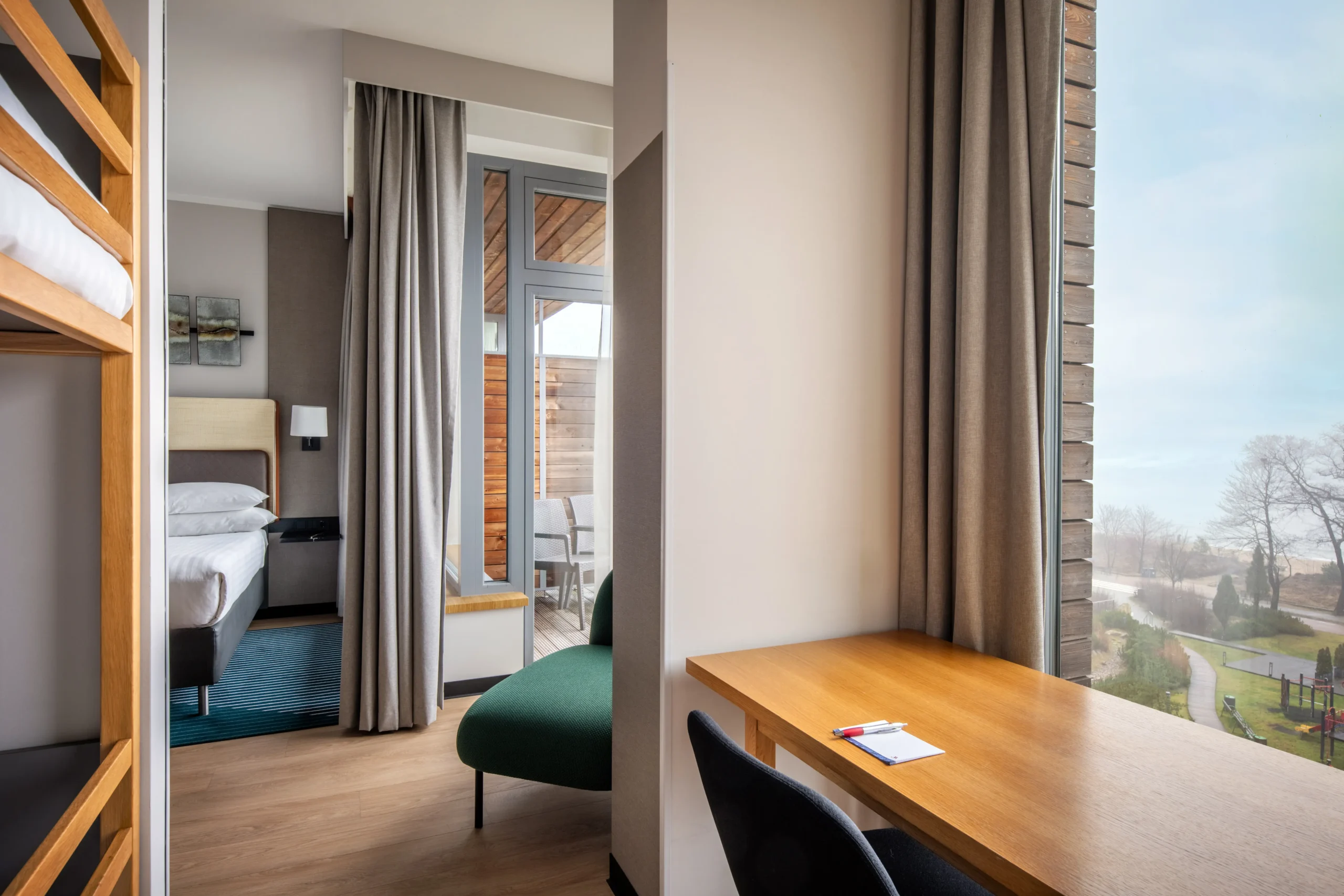 Wnętrze pokoju hotelowego z biurkiem, krzesłem, fotelem, łóżkiem i tarasem – Aranżacje i wykończenia obiektów komercyjnych