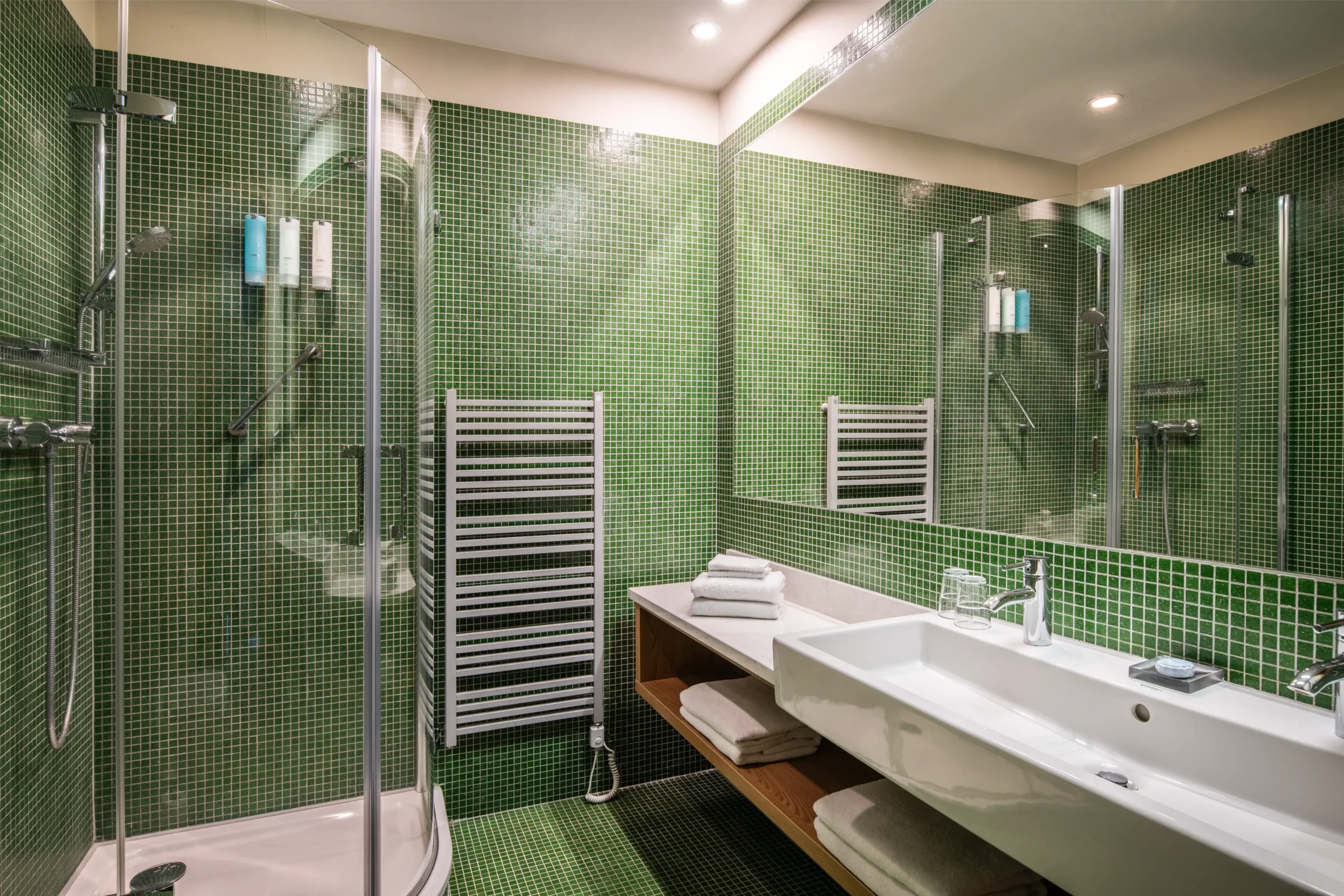 Nowoczesna łazienka z zielonymi mozaikowymi płytkami, kabiną prysznicową, podgrzewaczem na ręczniki i umywalką Aranżacja łazienki