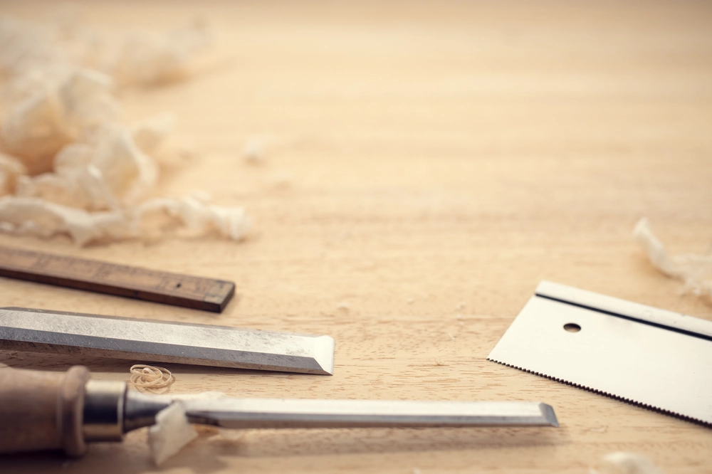 Zestaw dłut stolarskich i wiórów drewnianych na blacie roboczym