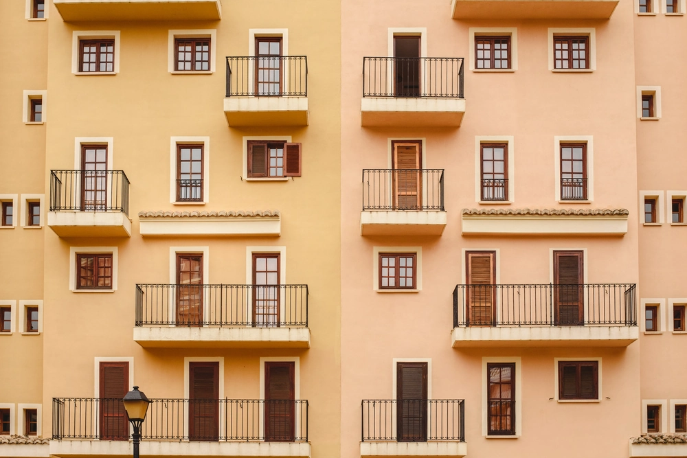 Elewacje pastelowego budynku wielorodzinnego z balkonami i oknami w nowoczesnym stylu