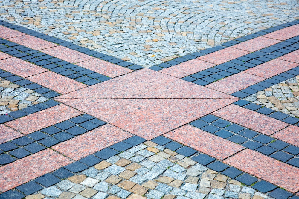 Geometryczny układ różowych płyt granitowych i ciemnych kostek brukowych na placu – Kostka brukowa