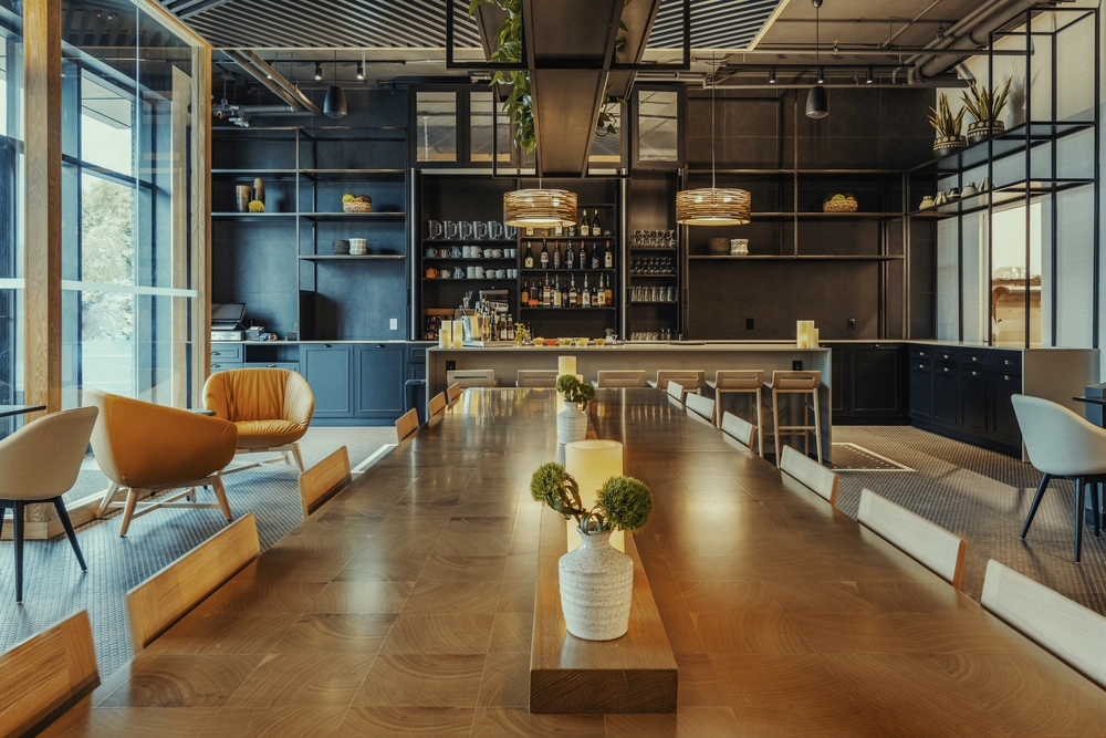 Wykończenie lokalu usługowego z długim drewnianym stołem, krzesłami i barem w nowoczesnym wnętrzu