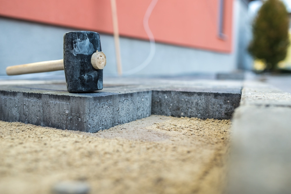 Układanie kostki brukowej na podsypce piaskowej z gumowym młotkiem
