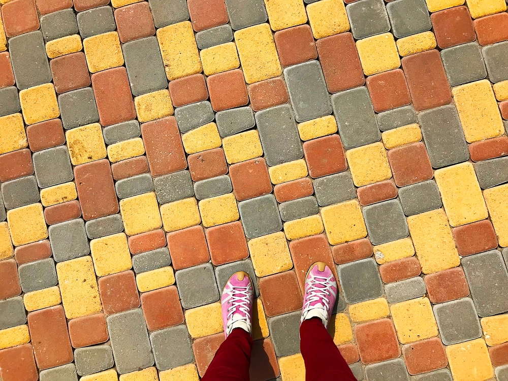 Widok z góry na różowe buty stojące na wielobarwnej kostce brukowej