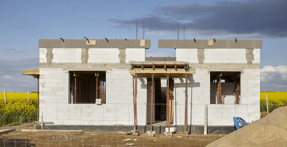 Budowa domów: parterowy szkielet budynku z białych bloczków gazobetonowych, z podporami i deskowaniem