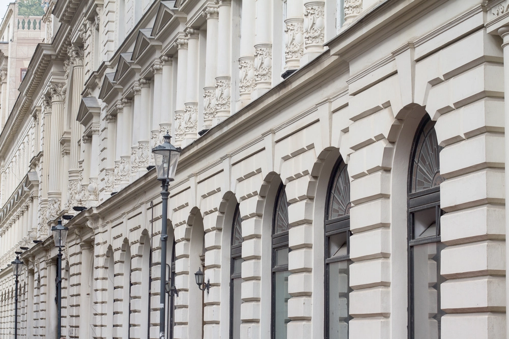 Elewacje klasycznej fasady z białym tynkiem, ozdobnymi kolumnami, łukowymi oknami i latarniami ulicznymi