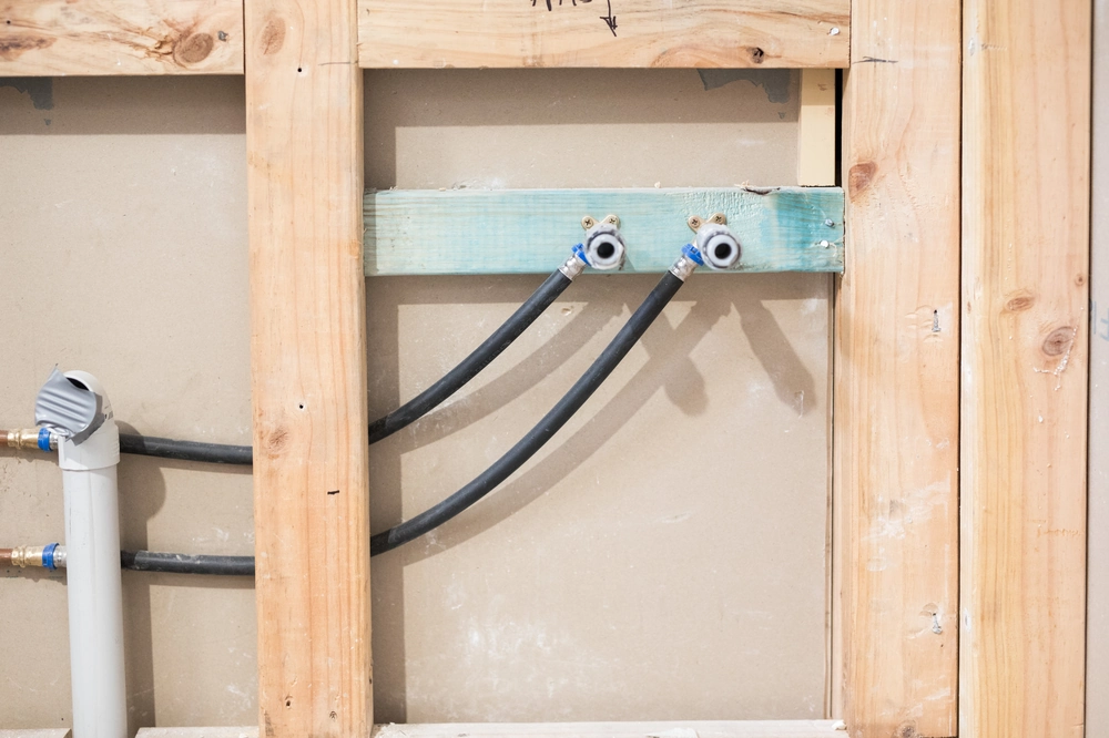 Instalacje hydrauliczne podtynkowe: dwa piony z elastycznymi rurami i odpływ PVC w ścianie