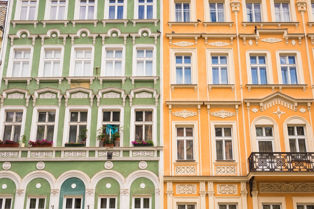 Elewacje żółtego i zielonego budynku z ozdobnymi detalami, oknami i balkonami