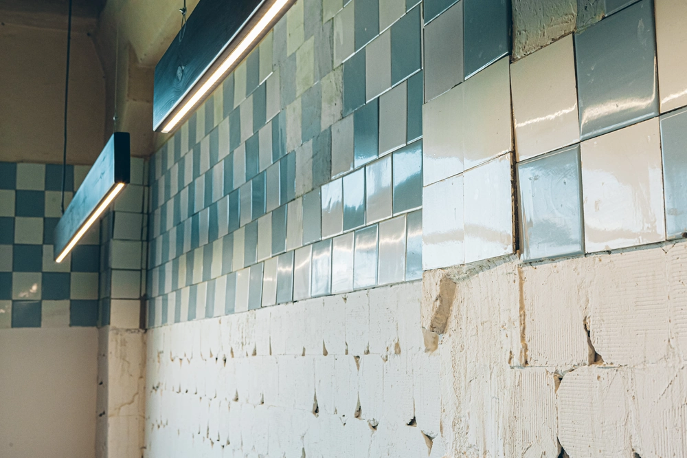 Częściowo położone niebiesko-białe płytki ceramiczne na ścianie podczas układania płytek