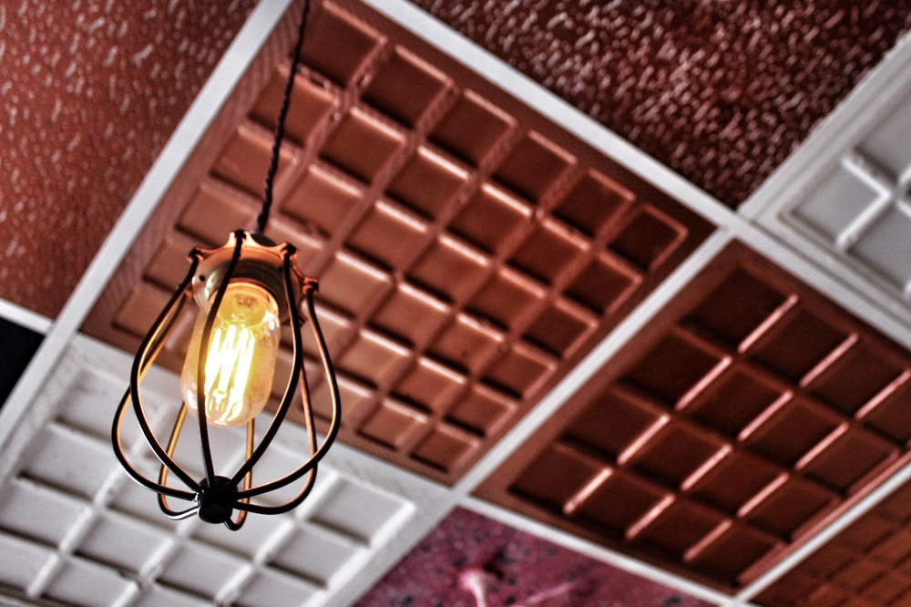 Wisząca lampa dekoracyjna z żarówką na tle dwukolorowego sufitu kasetonowego