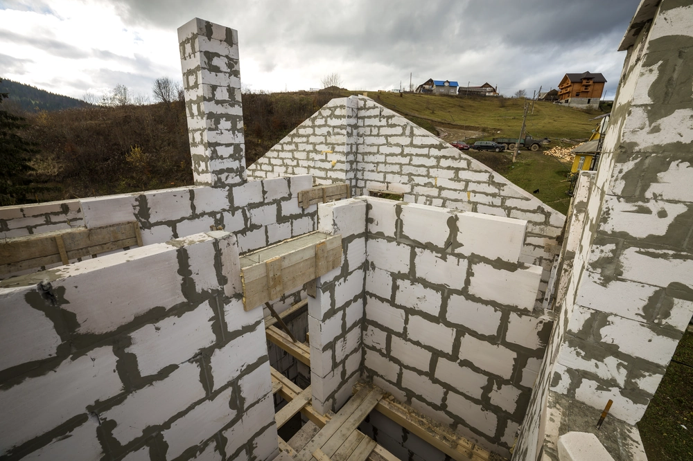Murowanie ścian budynku z biało-szarych bloczków betonowych w trakcie budowy