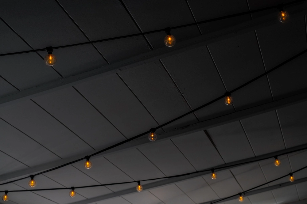 Sufity kasetonowe w odcieniach szarości z dekoracyjnym oświetleniem w postaci wiszących żarówek